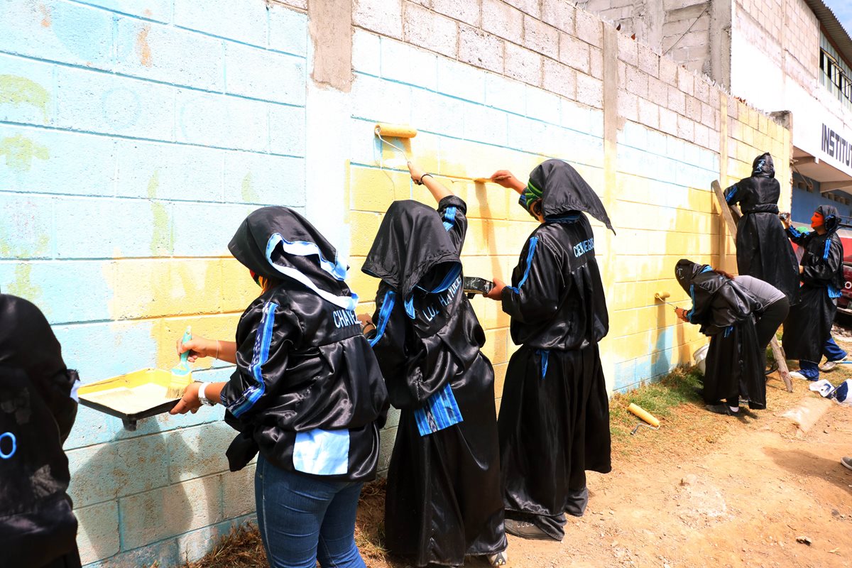 Grupo de encapuchados de la Facultada de Humanidades del Cunoc pintan la pared de la Escuela Oficial de Párvulos Lucas T. Cojulun, en Quetzaltenango. (Foto Prensa Libre: Carlos Ventura)