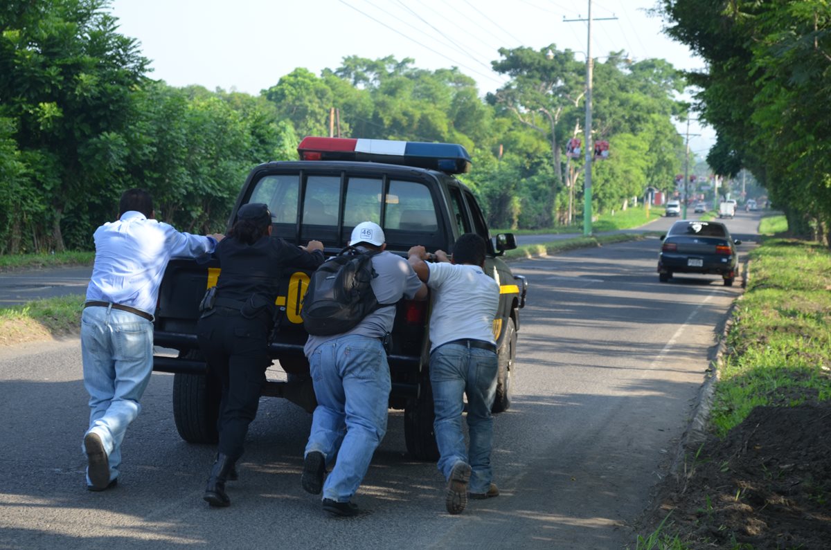 Policías y civiles empujan una autopatrulla con fallos mecánicos. (Foto Prensa Libre: Hemeroteca PL)