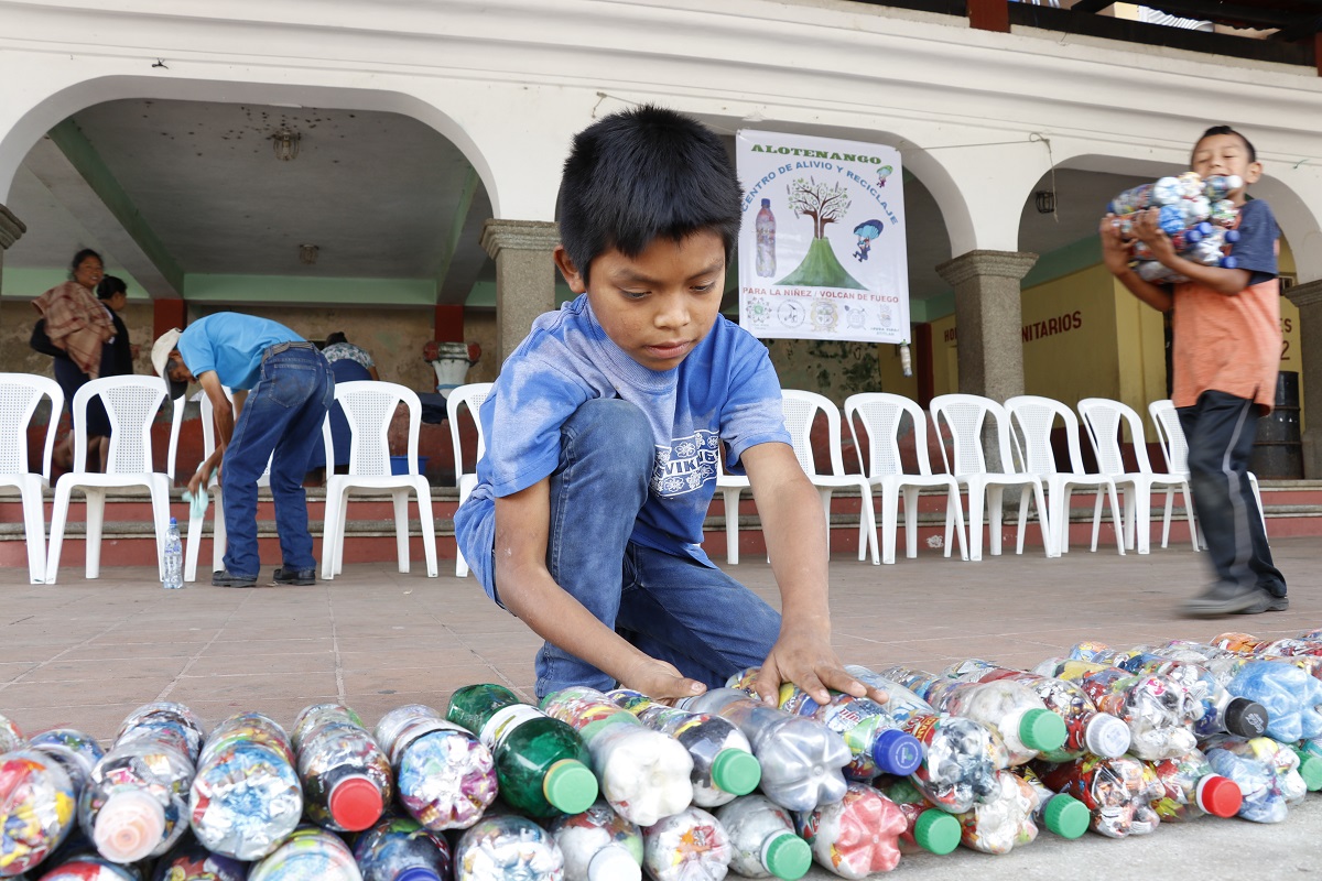 Niños de San Juan Alotenango ayudan a ordenar los ecoladrillos que serán utilizados para construir el módulo de lectura. (Foto Prensa Libre: Julio Sicán).