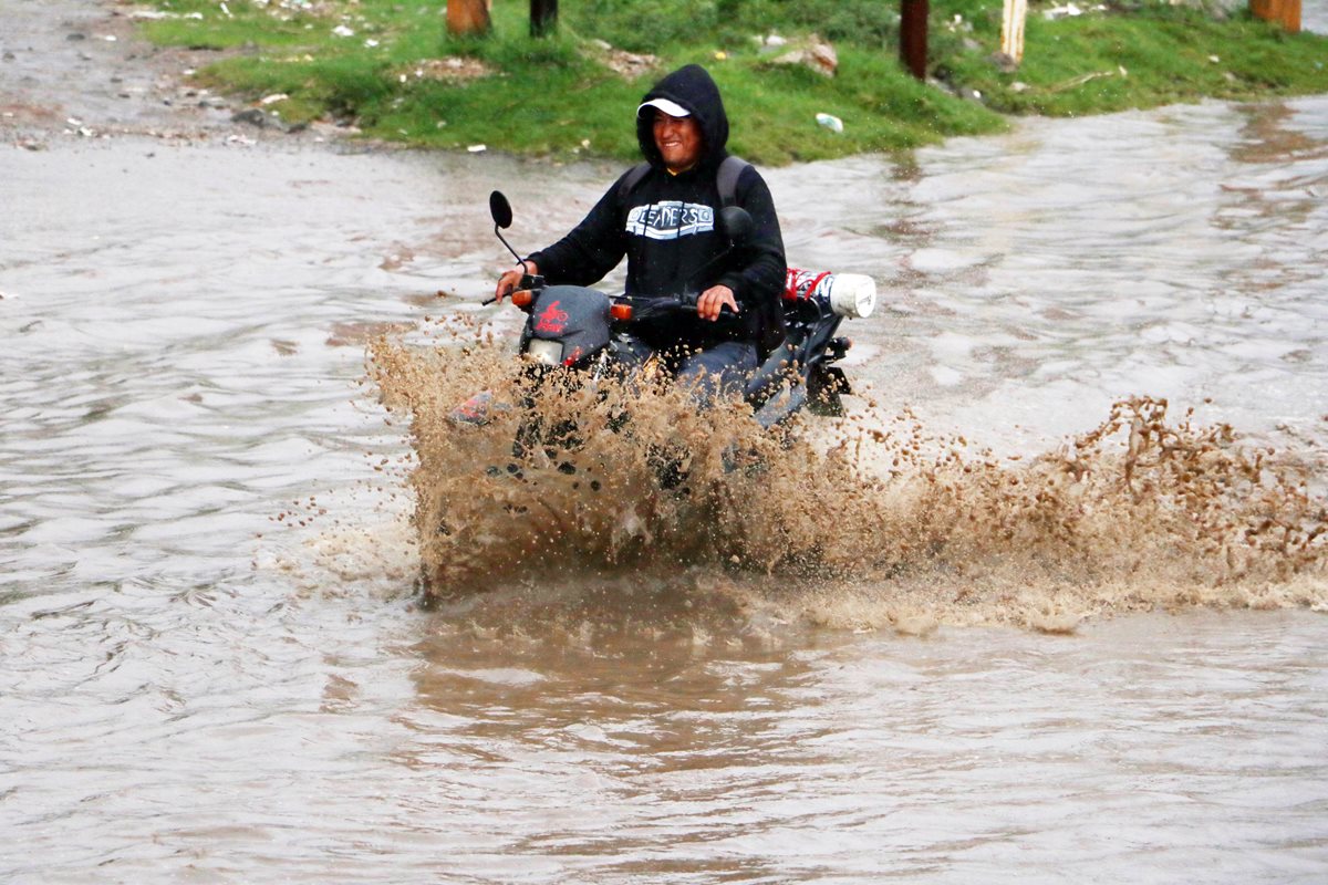 Hombre cruza en motocicleta la inundada carretera principal de Valle de Palajunoj en la cabecera de Quetzaltenango. (Foto Prensa Libre: Carlos Ventura)