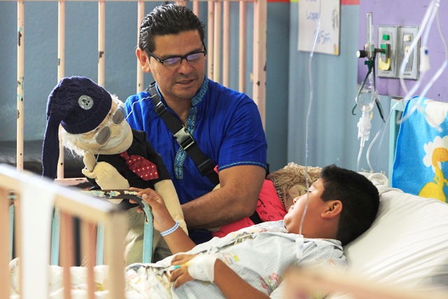 El abuelo Lalito conversa con Julio García, de 10 años, en la Pediatría del hospital mientras Luis Fernando Reyes Cáceres da vida con su arte al personaje. (Foto Prensa Libre: Carlos Hernández)