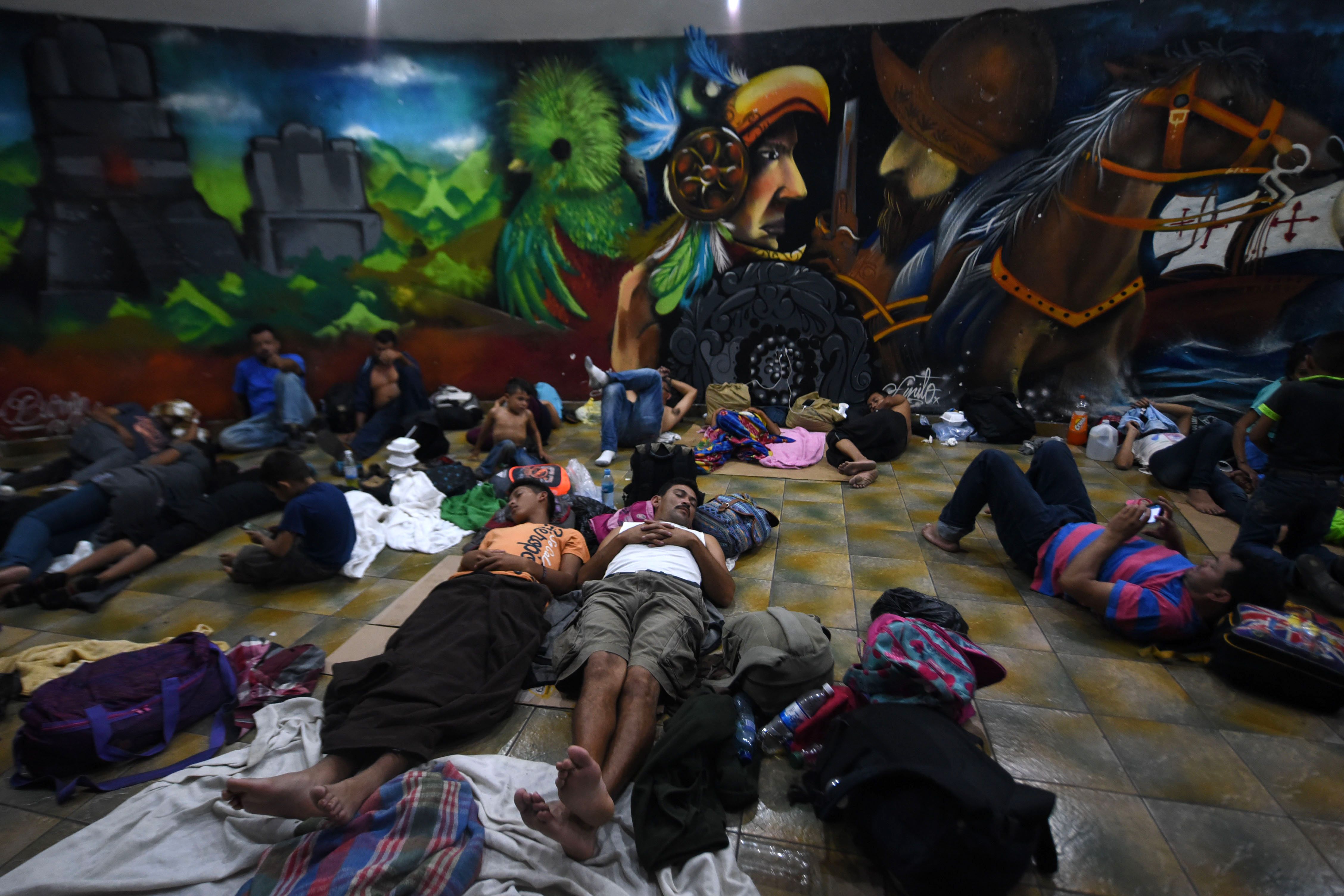 Honduran migrants heading to the United States with a second caravan lie on the ground at the central park of Ciudad Tecun Uman, Guatemala, on the border with Mexico, on January 17, 2019. - A new caravan of Central American migrants trying to reach the United States made its way across Guatemala on January 17, with the first members crossing into southern Mexico. (Photo by Johan ORDONEZ / AFP)