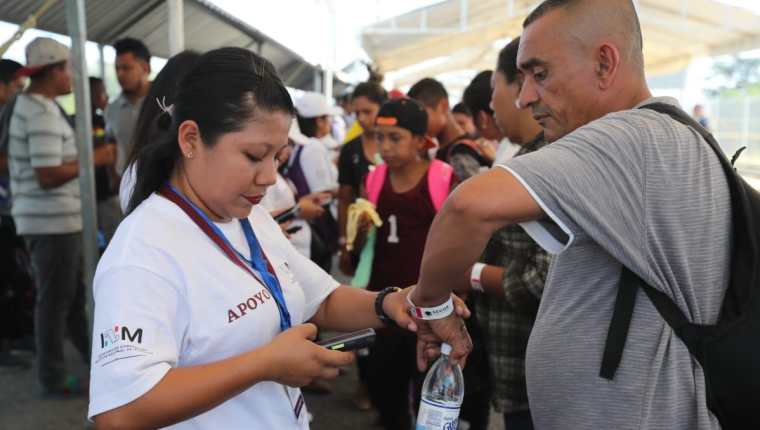 Varios delegados del Instituto Nacional de Migración de México orientan a migrantes hondureños que quieren ingresar a ese territorio. (Foto Prensa Libre: Erick Ávila) 