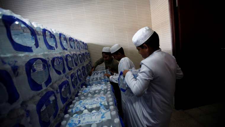 Niños musulmanes estiban cajas de agua en la mezquita de la fundación islámica Jummah Masjid. (Foto Prensa Libre: EFE)