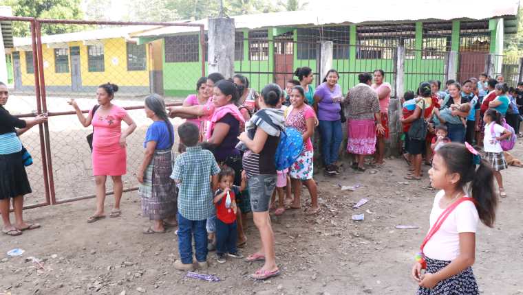 Una de las madres de familia muestra el candado que colocaron en el portón de la escuela de la aldea Morazán. (Foto Prensa Libre: Cristian Soto). 