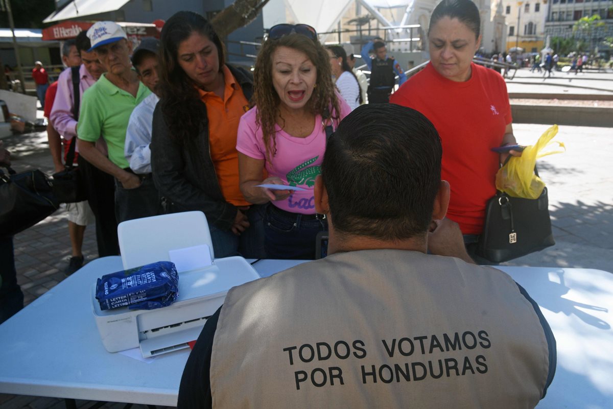 Un trabajador del Tribunal Supremo Electoral (TSE) de Honduras proporciona información a los ciudadanos sobre su lugar de votación. (Foto Prensa Libre: AFP)