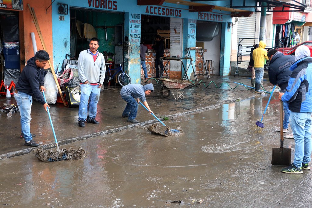 Comerciantes de Xelajú retiran el lodo que arrastró la correntada hacia sus locales en la 6ª avenida de la zona 2. (Foto Prensa Libre: Carlos Ventura)