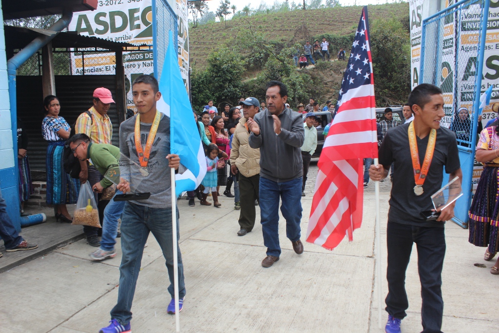 Los dos atletas son recibidos por pobladores en Santa Lucía Utatlán. (Foto Prensa Libre: Ángel Julajuj).