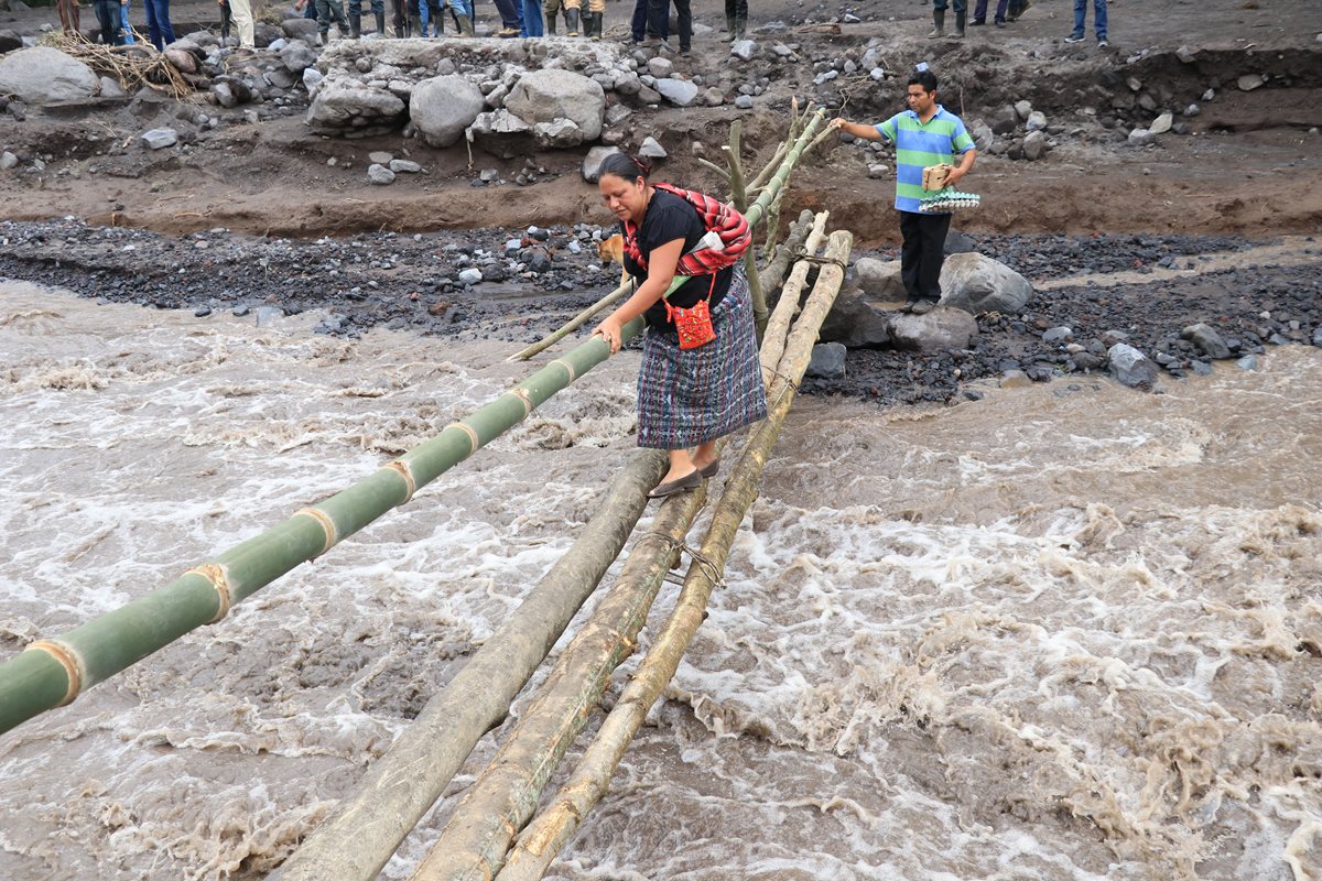 Mujer toma sus precauciones al momento de atravesar el paso provisional sobre el río Ceniza. (Foto Prensa Libre: Enrique Paredes).