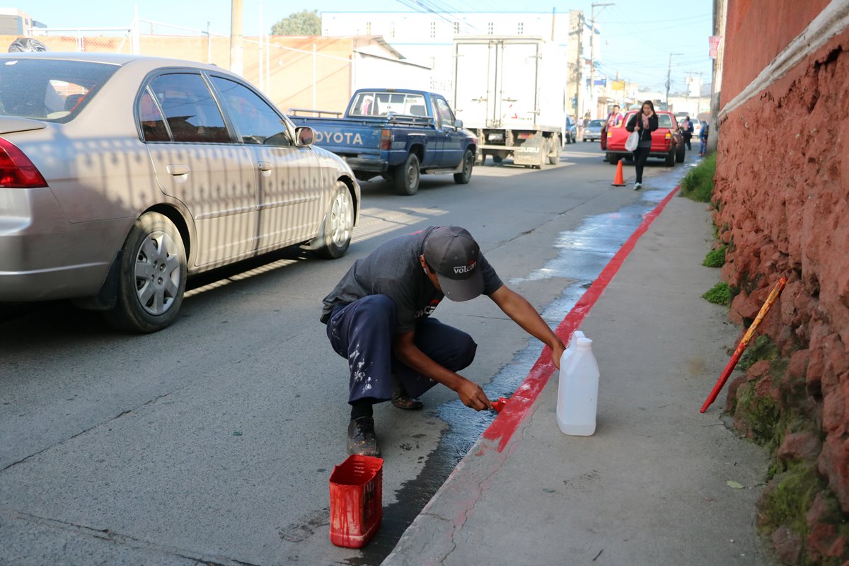 Personal de la PMTQ pinta rojo las orillas de las aceras, para restringir las áreas de parqueo en la diagonal dos, zona 3 de Quetzaltenango. (Foto Prensa Libre: Carlos Ventura)