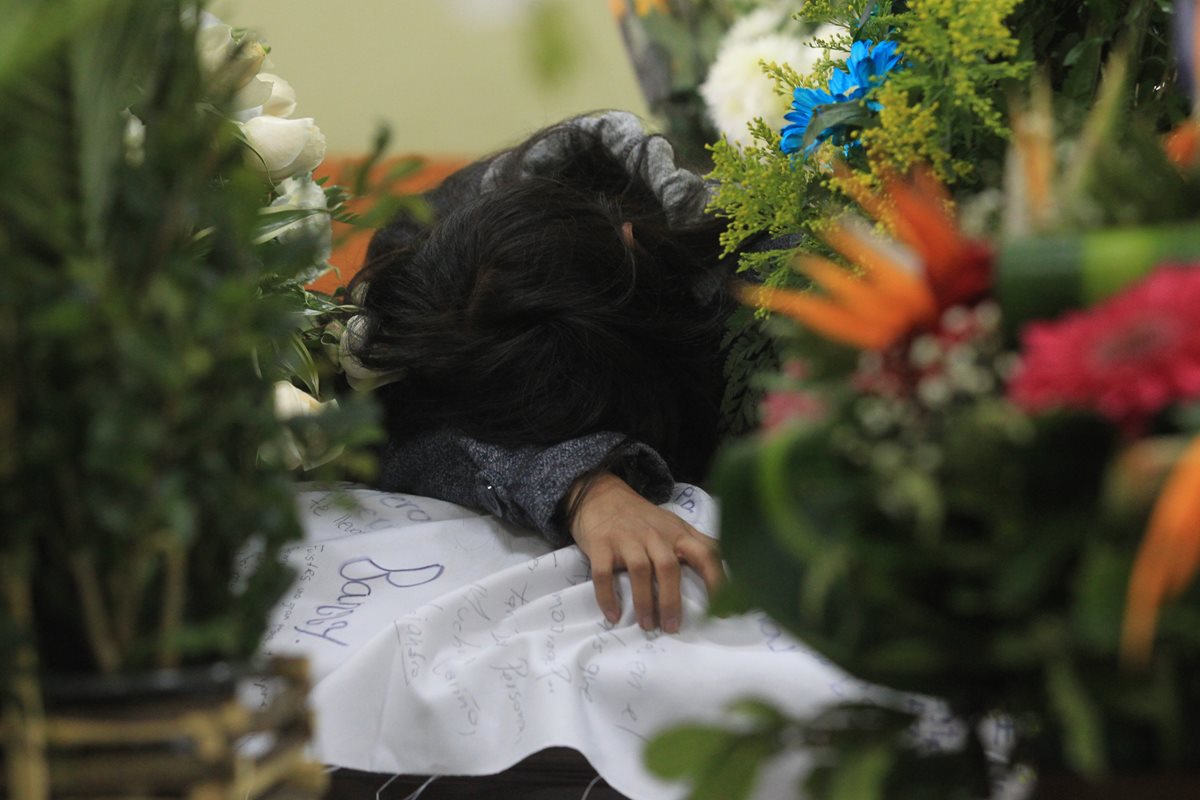 Una familiar  de Nimcy Marroquín llora sobre el féretro, que fue cubierto con una manta firmada por todos sus amigos del colegio. (Foto Prensa Libre: Estuardo Paredes)