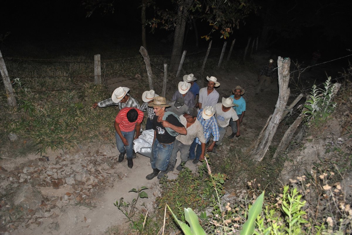 Un grupo de vecinos traslada el cadáver de una de las dos víctimas. (Foto Prensa Libre: Mario Morales).