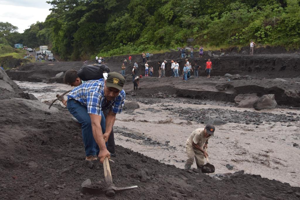 Pobladores de las faldas del Volcán de Fuego trabajan para habilitar paso hacia nueve aldeas incomunicadas por correntadas de material volcánico. (Foto Prensa Libre: Enrique Paredes)