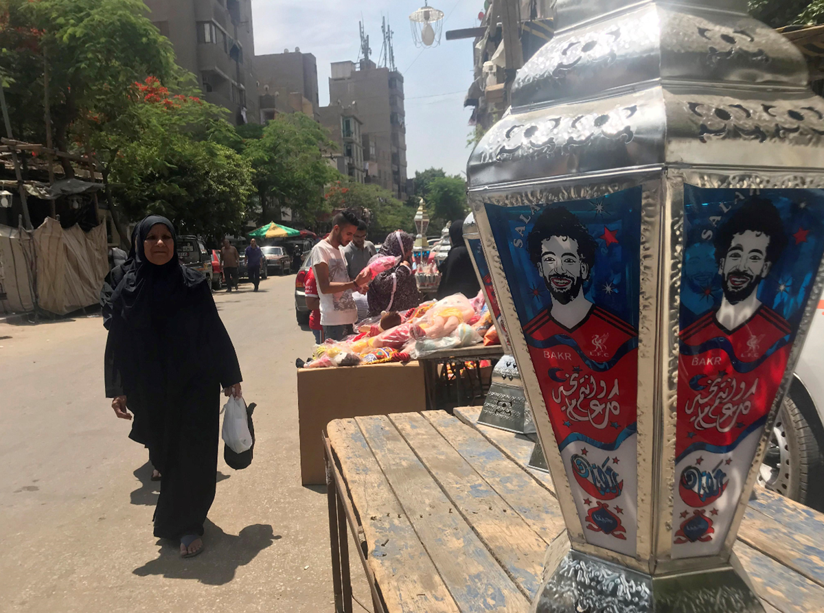 Una mujer observa un farol de colores, típico del mes sagrado de Ramadán, en el barrio islámico de El Cairo, con el rostro de Mohamed Salah. (Foto Prensa Libre: EFE)