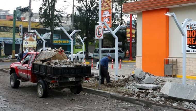 Un trabajadore retira restos de mesas y bancas frente a una pizzería que se halla en la zona 3 de Quetzaltenango. (Foto Prensa Libre: Carlos Ventura)