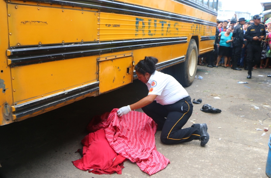 Una socorristas resguarda el cadáver del niño, quien murió al ser atropellado por un bus. (Foto Prensa Libre: R. Miranda)