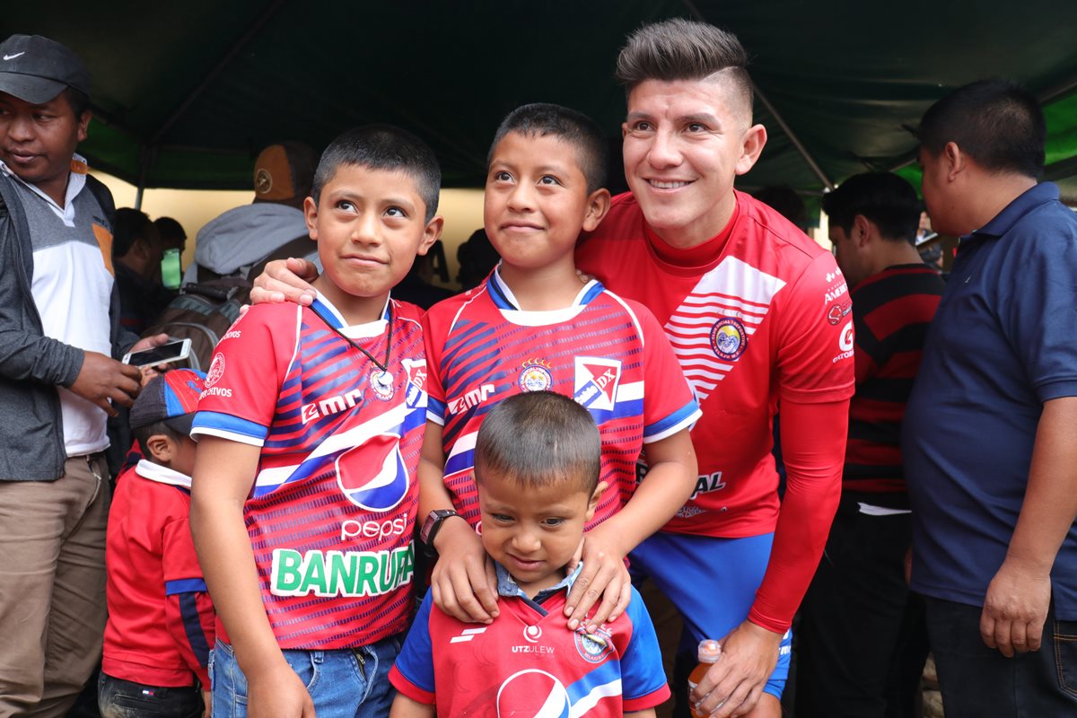 Kristian Guzmán, posa para una fotografía con niños que llegaron identificados con la camisola de Xelajú y quienes más disfrutaron del juego. (Foto Prensa Libre: Raúl Juárez)