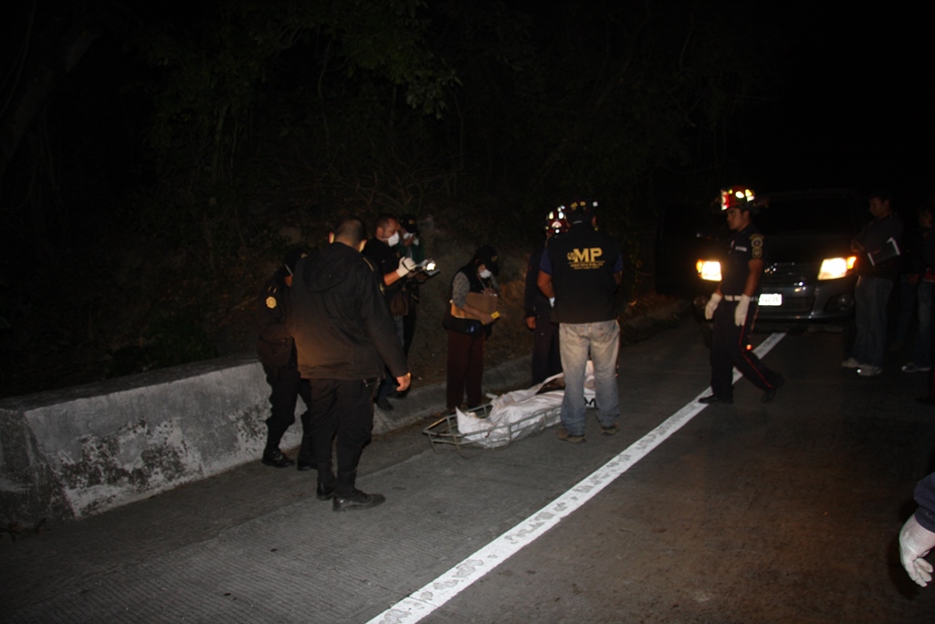 Investigadores inspecciones el cadáver localizado en la ruta a Antigua Guatemala, Sacatepéquez. (Foto Prensa Libre: Renato Melgar).