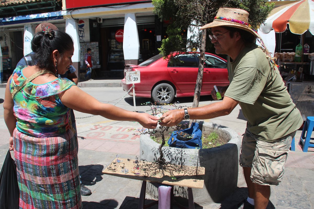El Chileno Luis Vega vende una de sus artesanías a una vecina, en el parque central de Huehuetenango, donde se instala para exhibir sus productos elaborados con alambre.(Foto Prensa Libre: Mike Castillo)