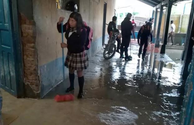 Una estudiante saca parte del agua que inundó la escuela en Chiantla, Huehuetenango. (Foto Prensa Libre: Mike Castillo)