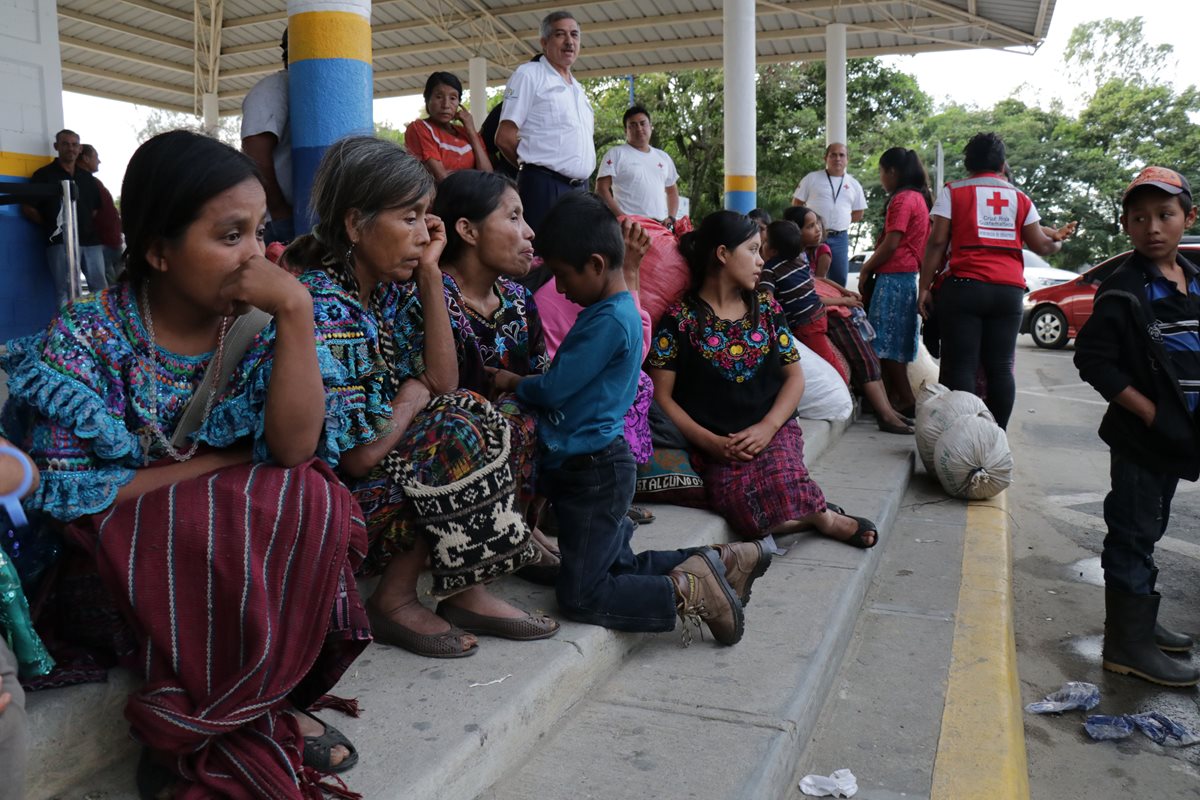 Mujeres y niños, junto a costales donde guardan ropa, esperan en la frontera de Corinto, entre Honduras y Guatemala, luego de que fueran víctimas de trata de personas y explotación laboral en aquel país. (Foto Prensa Libre: Dony Stewart)