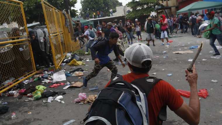 Migrantes hondureños se enfrentan a agentes de la Policía Nacional Civil quienes impiden el paso en la frontera entre Guatemala y México. (Foto Prensa Libre: EFE)