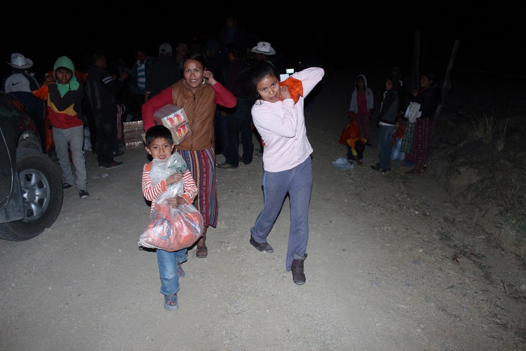 Tres de los pobladores que resultaron afectados por el fenómeno natural trasladan la ayuda recibida. (Foto Prensa Libre: Óscar Figueroa).