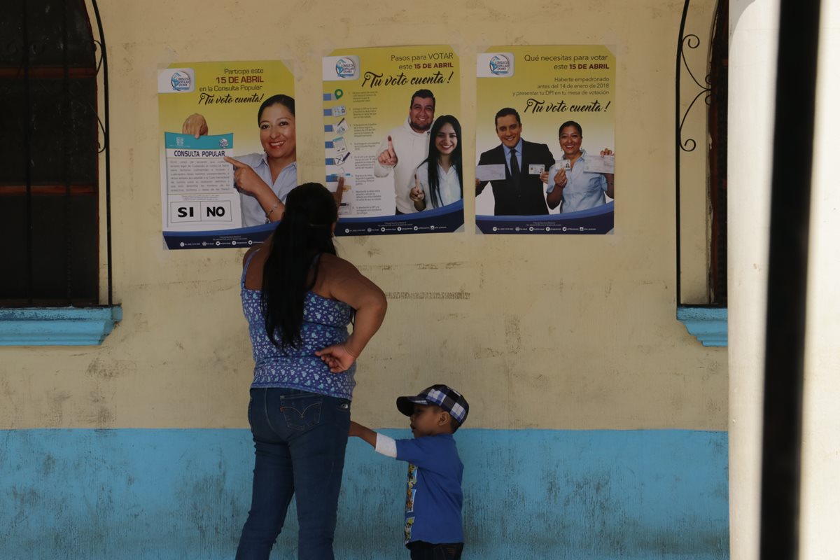 Una madre de familia lee uno de los carteles que el Tribunal Supremo Electoral instaló en la entrada a la comuna de El Tejar, Chimaltenango. (Foto Prensa Libre: Víctor Chamalé)