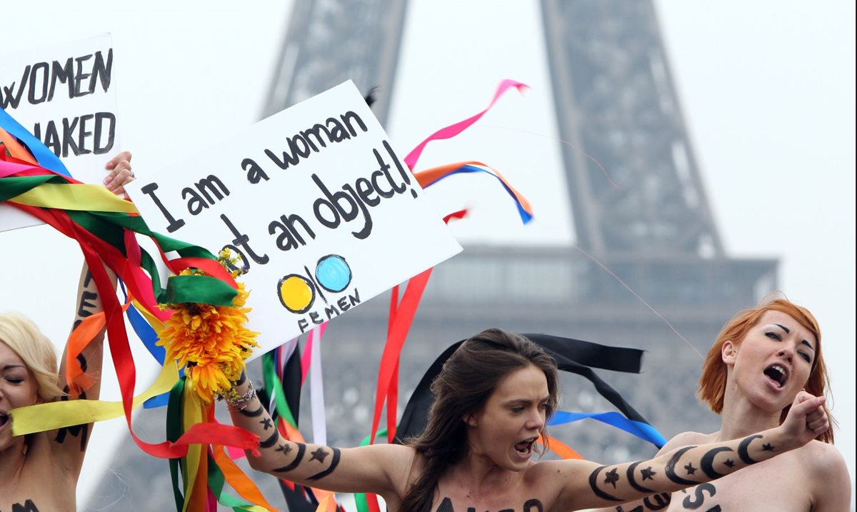 Foto tomada el 31 de marzo de 2012, Oksana Shachko (C) con activistas topless del movimiento de Femen sostiene carteles mientras protestan en la torre Eiffel en París.(Foto Prensa Libre:AFP).