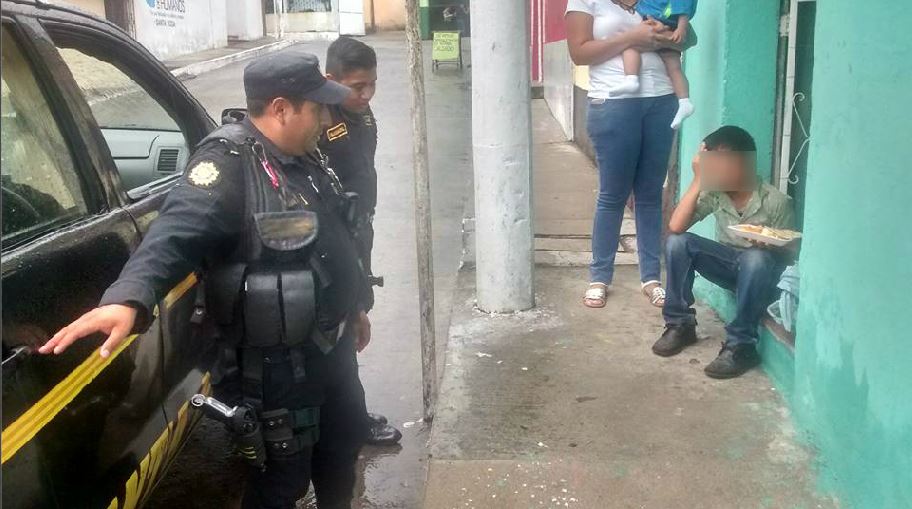 Policías hacen preguntas al niño que, sentado, trata de buscar consuelo por la pérdida del producto luego de que fue asaltado. (Foto Prensa Libre: Cortesía)