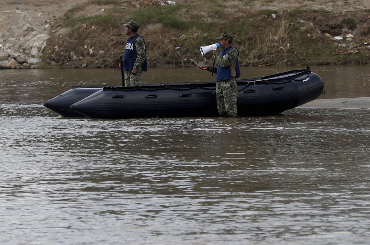 Integrantes de la Marina de México advierten por megáfonos a los hondureños que eviten cruzar. (Foto Prensa Libre: EFE)