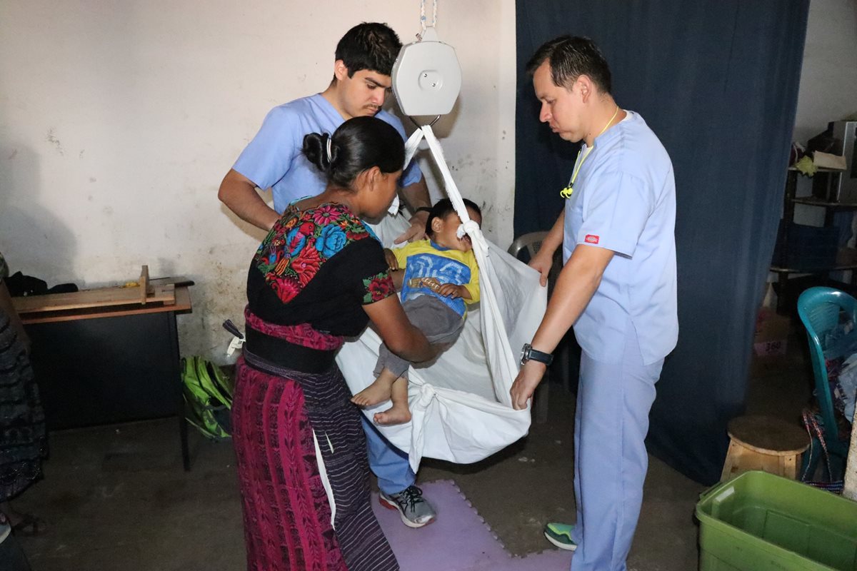 Dos médicos del programa Pop Wuj ayudan a una mujer a pesar a su hijo. (Foto Prensa Libre: María José Longo)