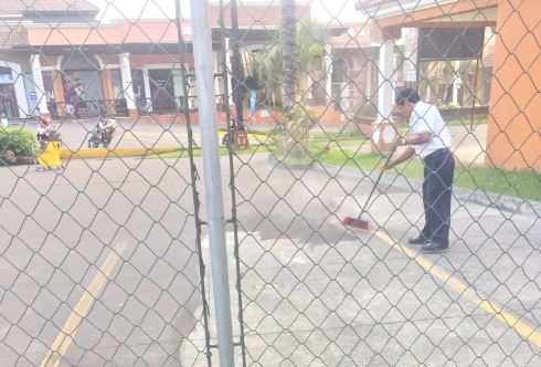 Un trabajador limpia de arena y ceniza un estacionamiento en Amatitlán. (Foto: HenryENorman)