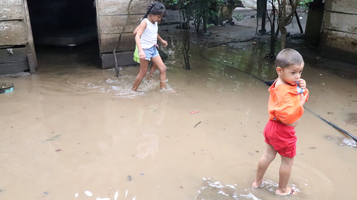 Niños caminan sobre el agua que se acumuló en el patio de su vivienda. (Foto Prensa Libre: Cristian I. Soto)
