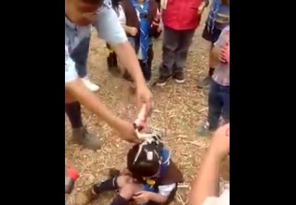 Captura del video donde una mujer adulta vacía una botella de refresco a la pequeña quien llora desesperadamente. (Foto: Faceook).