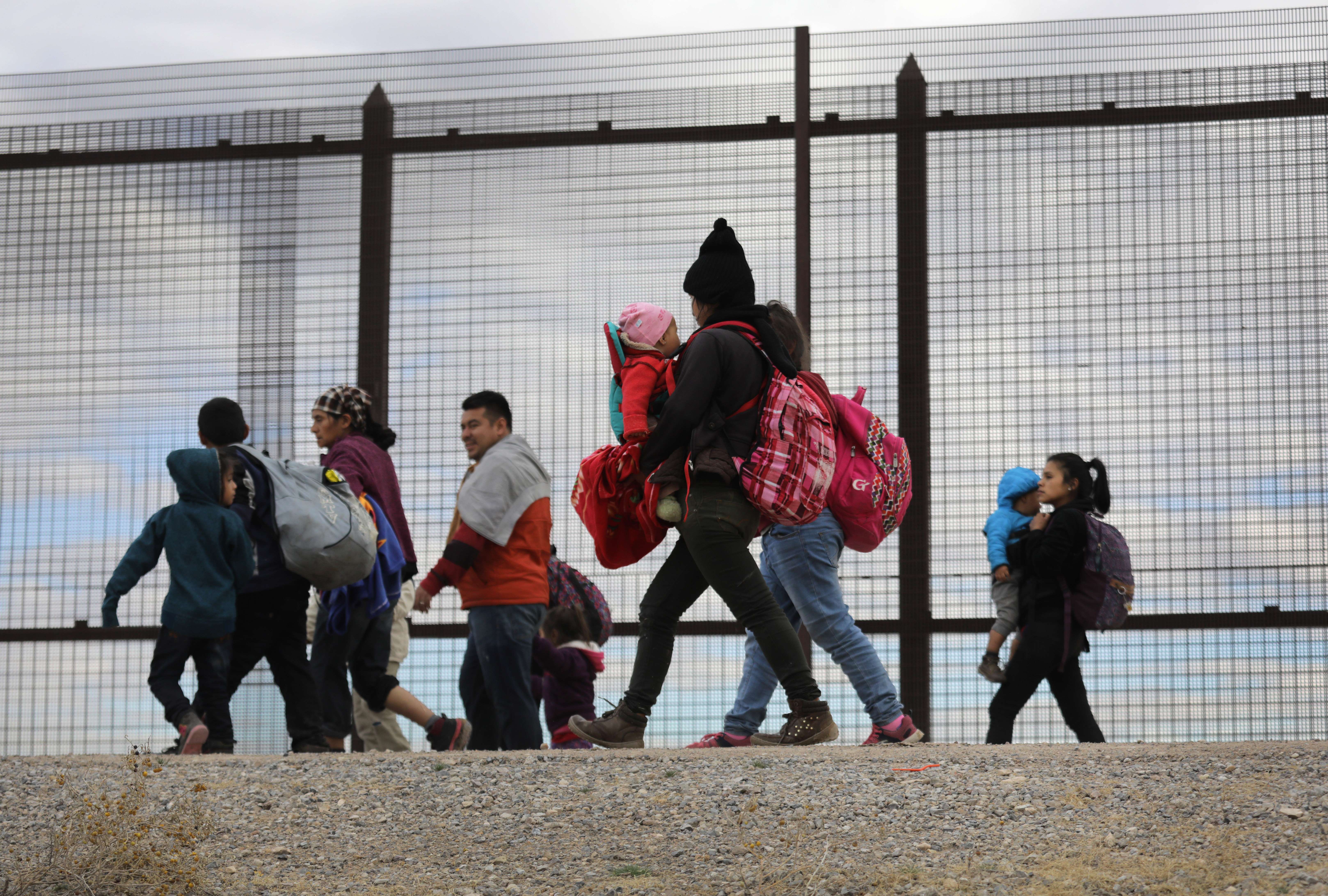 Migrantes centroamericanos caminan a lo largo del muro en El Paso, Texas. (Foto Prensa Libre: AFP)