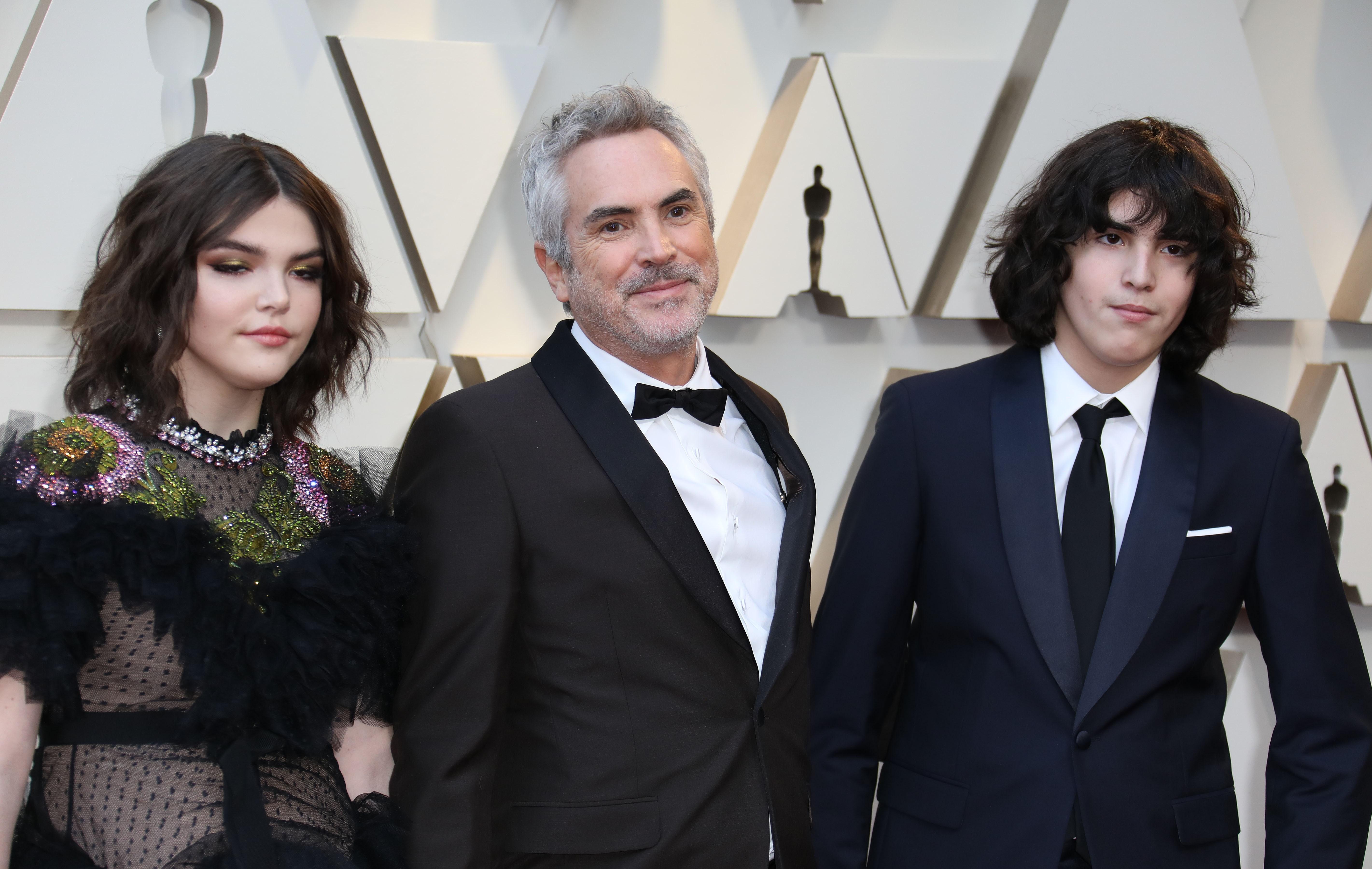El director mexicano Alfonso Cuarón (centro) y sus hijos, Olmo Teodoro (derecha) y Tess Bu (izquierda), posan a su llegada a la alfombra roja de los Premios Óscar. (Foto Prensa Libre: EFE)