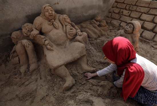 Rana Ramlawi, artista que realiza esculturas de arena relacionadas con el conflicto bélico del país, da los últimos retoques a su última obra en Gaza. EFE