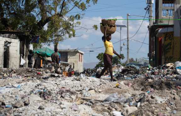 Una mujer camina sobre una calle completamente cubierta por escombros y basura, producto de las violentas protestas de la semana pasada. EFE