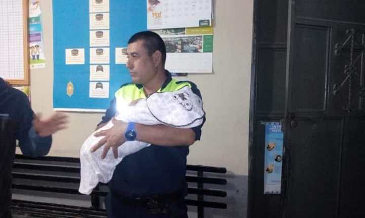 Agente de la PMT carga al bebé abandonado en Chicamán. (Foto Prensa Libre: Héctor Cordero). 
