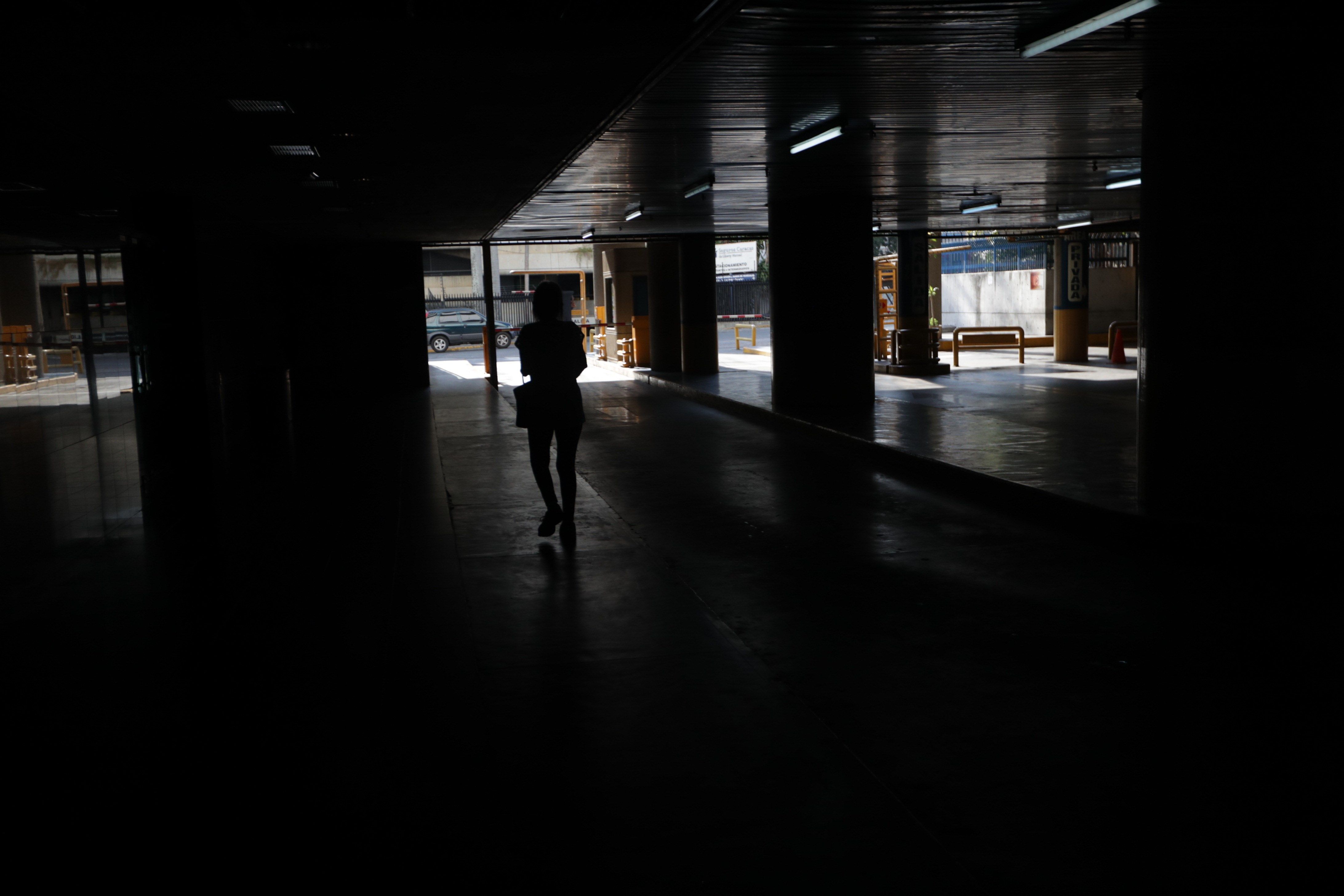 Una persona camina por un parqueo sin luz el sábado 9 de marzo en Caracas, Venezuela. (Foto Prensa Libre: EFE).