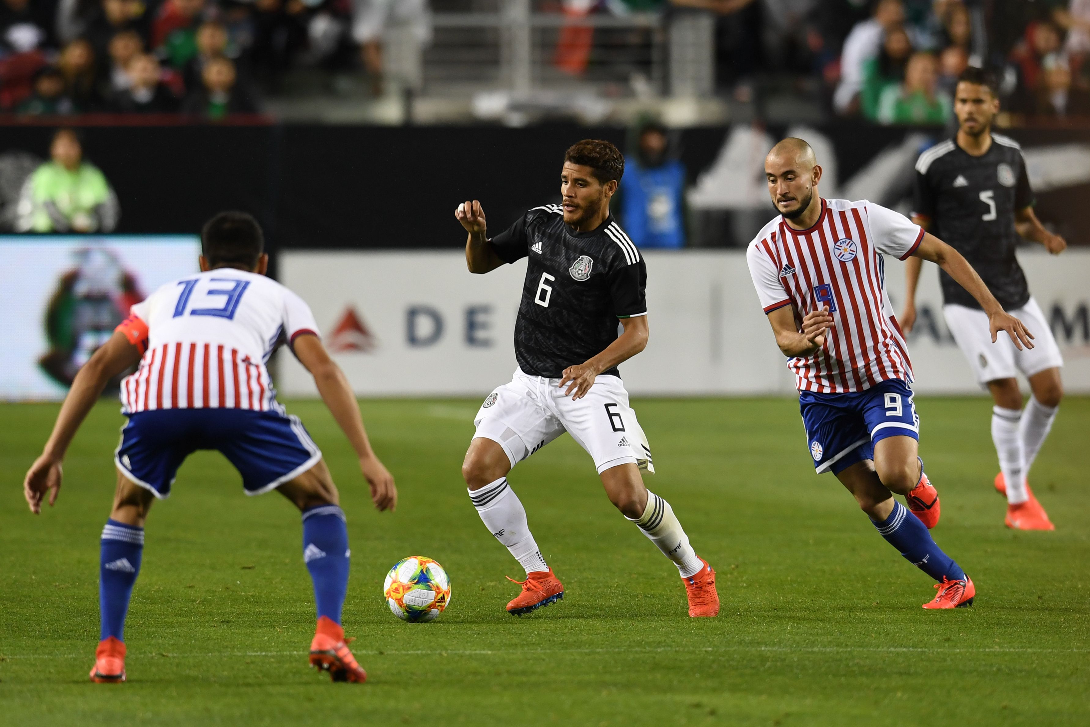Mexico's Jonathan Dos Santos (C) fights for the ball with Paraguay's Junior Alonso (L) and Carlos Gonzalez during the international friendly match between Mexico and Paraguay at Levi's Stadium in Santa Clara, California, on March 26, 2019. (Photo by Robyn Beck / AFP)