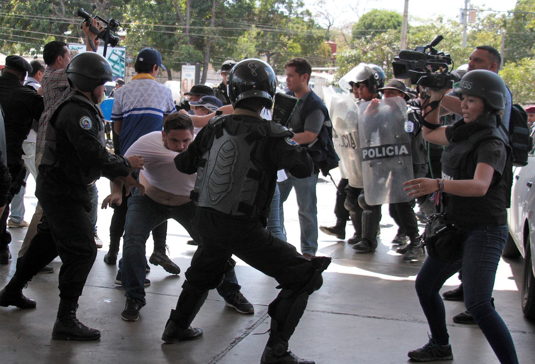 Oficiales de la policía antidisturbios de Nicaragua luchan con el camarógrafo de la AFP Luis Sequeira (L) y sus colegas ante una protesta convocada por grupos de la oposición para exigir al gobierno la liberación de los arrestados por participar en protestas. (Foto Prensa Libre: AFP)