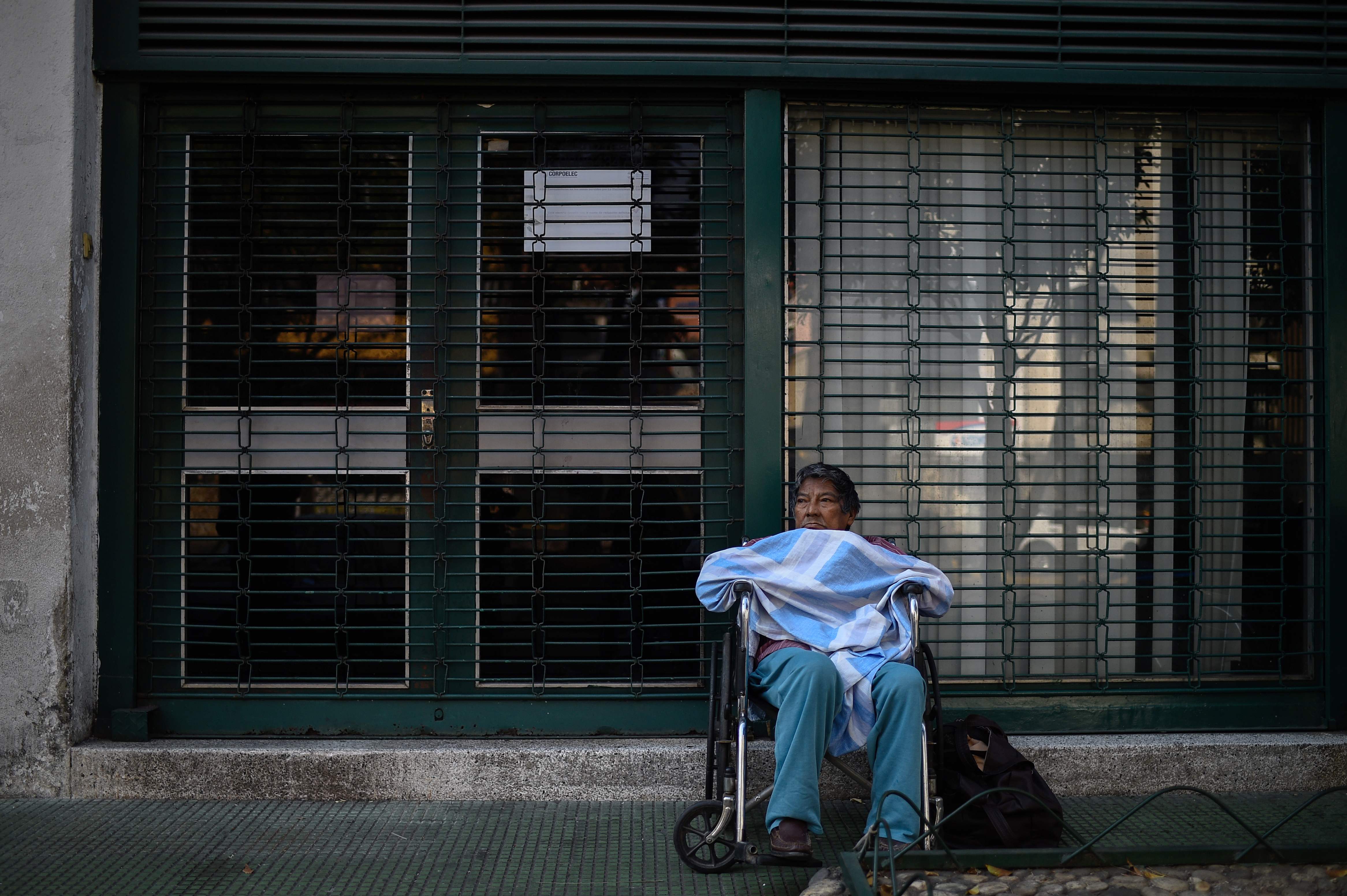 Un paciente en tratamiento de diálisis espera fuera de una clínica cerrada durante un apagón en Caracas. (Foto Prensa Libre: AFP)