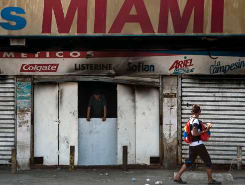 Un transeúnte mira una tienda cerrada, quemada durante el apagón que paralizó a Venezuela durante seis días.