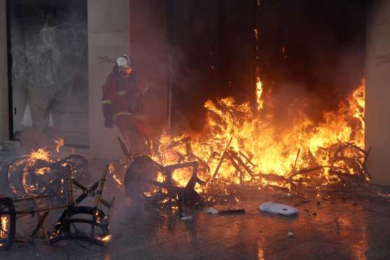 Un bomberos trata de apagar un incendio durante las protestas en los Campos Elíseos en Francia. Foto Prensa Libre: EFE