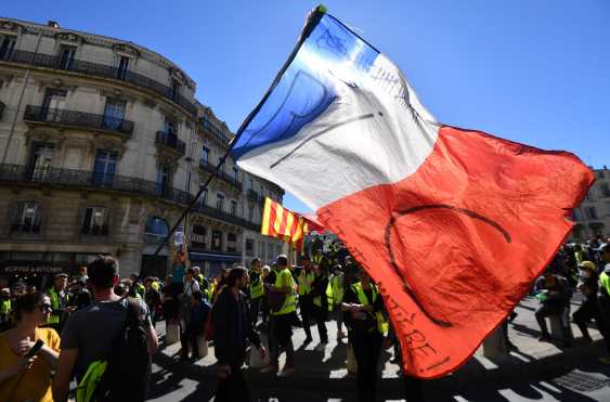 Un manifestante ondea una bandera nacional francesa que lee "RIC" (para el referéndum de ciudadanos iniciados) en Montpellier, sur de Francia. Foto Prensa Libre; AFP