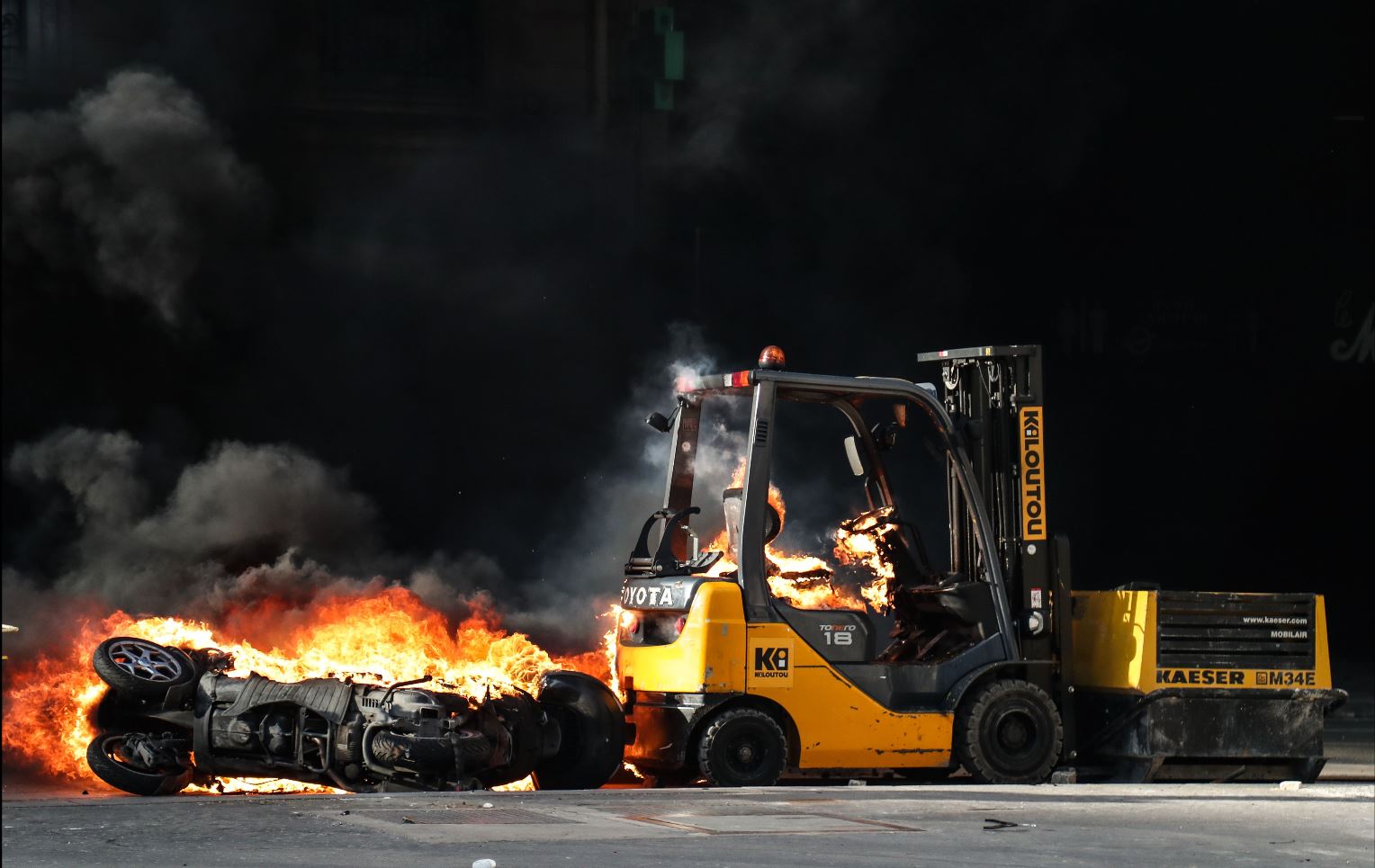 Una motocicleta y una carretilla elevadora incendiadas se muestran en la avenida Champs-Elysees en París, este 16 de marzo de 2019, durante  enfrentamientos entre las fuerzas de la policía antidisturbios y los manifestantes del chaleco amarillo. (Foto: AFP)