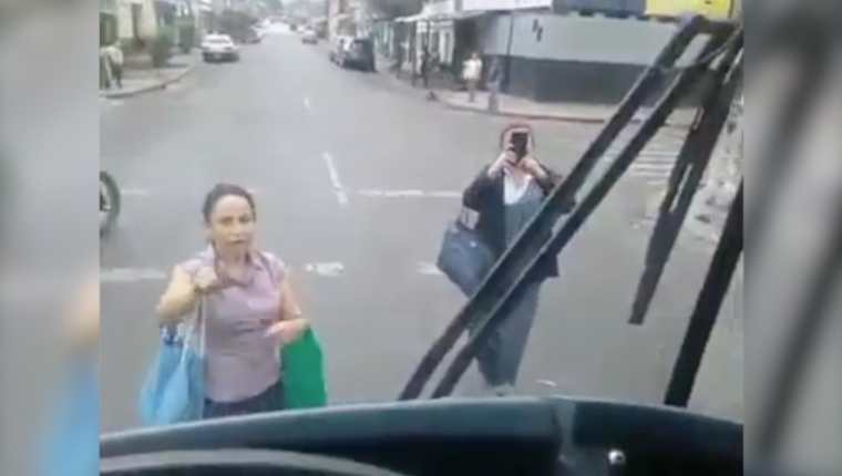Dos mujeres se paran a media calle en su intento de que el piloto del Express Naranjo les abra la puerta del bus. (Captura de pantalla)