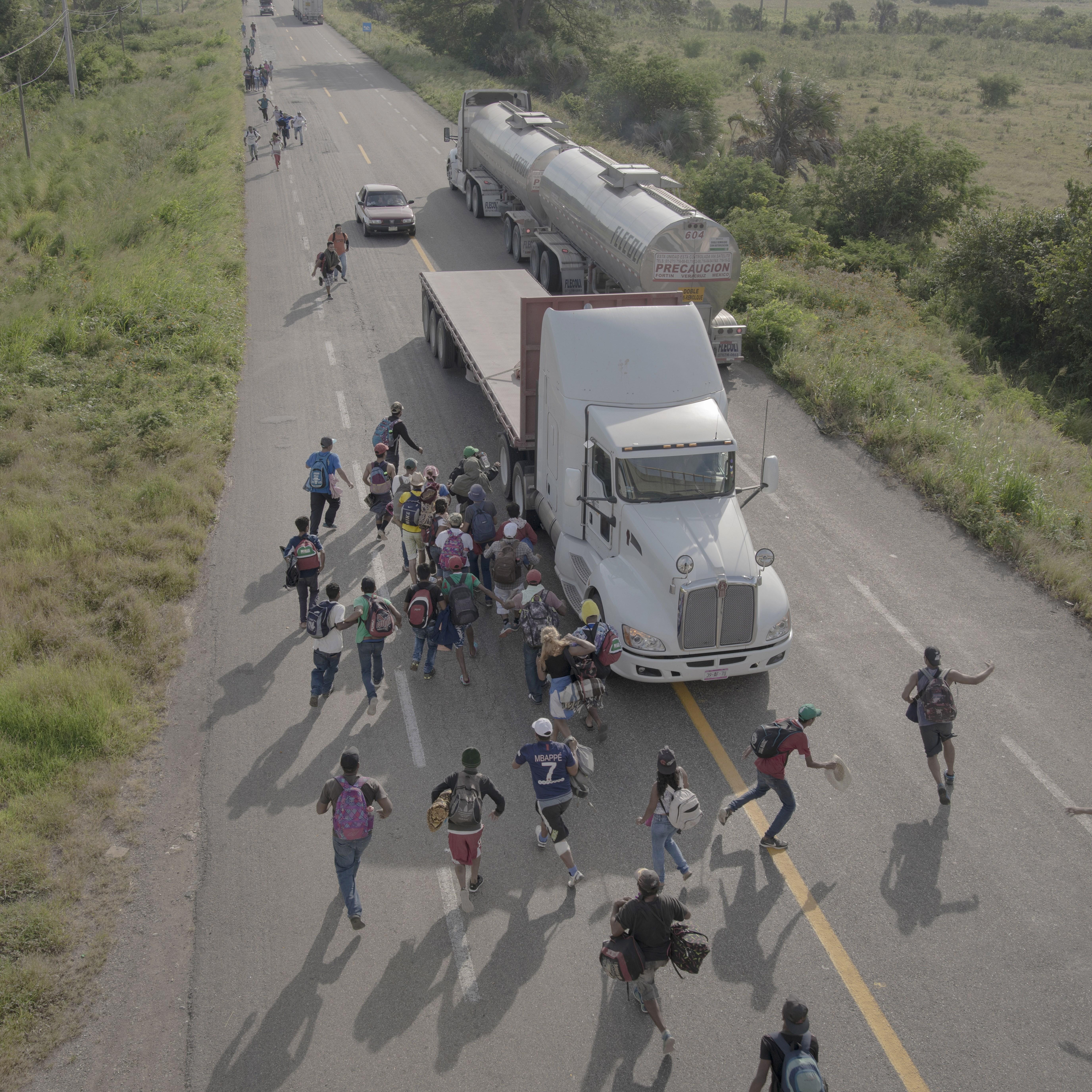 Migrantes corren hacia un camión para pedirles "jalón" en una carretera de Tapanatepec, México. (Foto Prensa Libre: EFE)